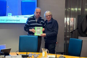 Willem Beekhuizen (rechts) biedt petitie aan, aan Evert Henrotte op 1 december 2025 tijdens Gemeenteraadsvergadering van de Gemeente Kaag & Braassem.